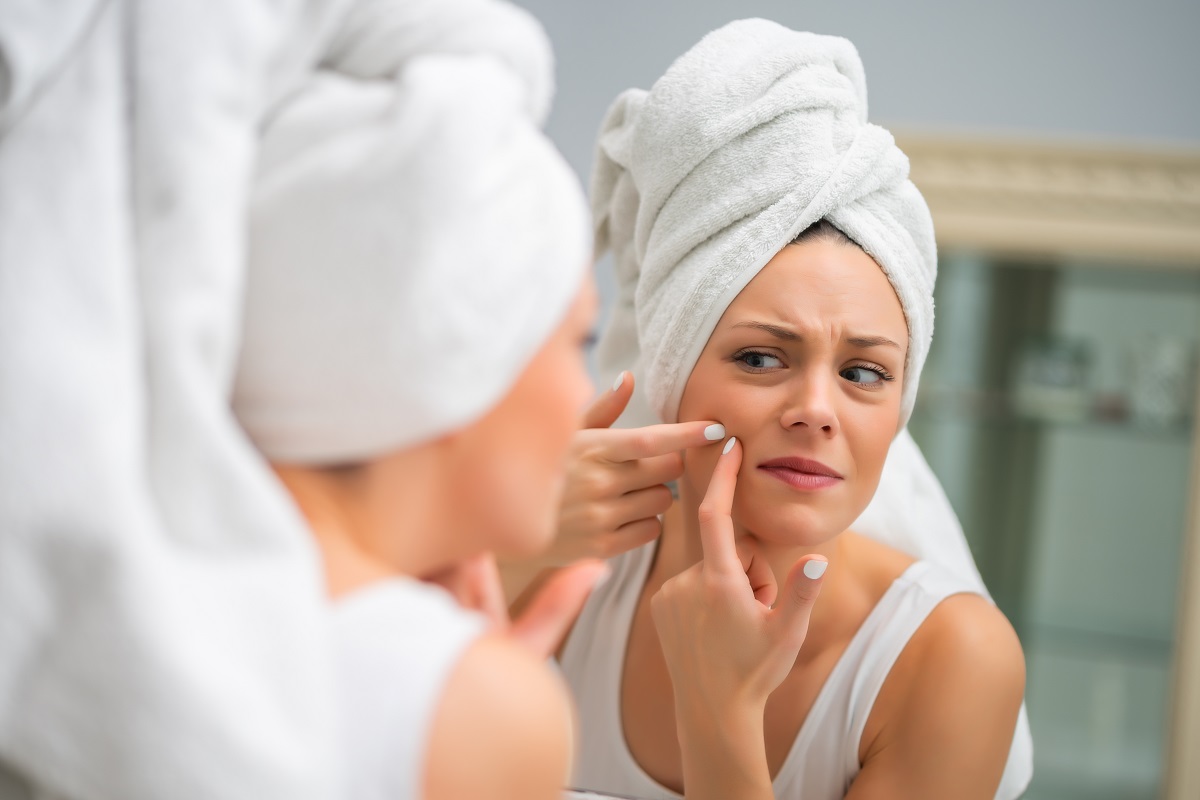Mulher no espelho antes de tratar a acne