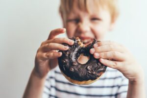 criança comendo alimento que contribui para a obesidade infantil